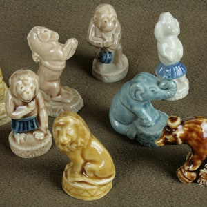Può includere: Una collezione di nove figurine in ceramica che raffigurano vari animali, tra cui una tigre, un leone, un elefante, una scimmia e un orso. Le figurine sono dipinte in varie tonalità di marrone, blu e bianco. Ogni figurina è in piedi su una piccola base.