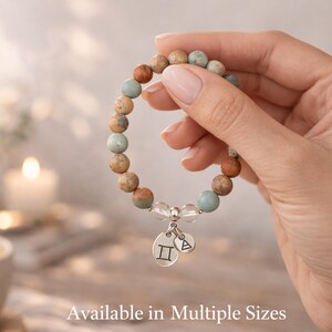 Gemini bracelet for women shown in hand with stretch fit and multiple size options, Aqua Terra Jasper and crystal quartz zodiac bracelet with Gemini charms