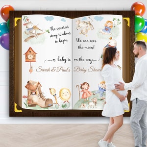 Może przedstawiać: Aquarela przedstawiająca otwartą książkę z motywem baby shower. Książka zawiera ilustracje krowy, zegara, buta i słońca. Tekst na książce brzmi: "Najsłodsza historia właśnie się zaczyna... dziecko jest w drodze" oraz "Baby Shower Sarah & Paula".