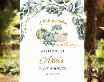 May include: A baby shower welcome sign on an easel. The sign features watercolor pumpkins and greenery with the text "A little pumpkin is on the way." Below, it reads "Welcome to Aria's Baby Shower" and the date 08.08.2025.
