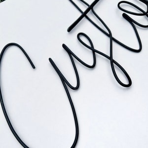 May include: Black metal wire word art spelling out the word "Custom".