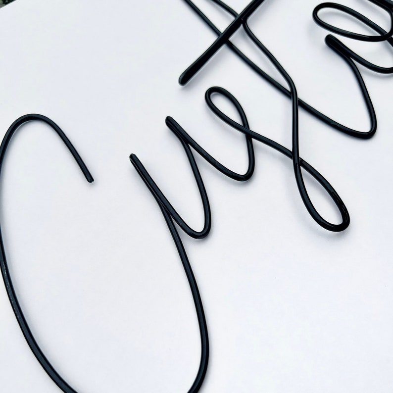 May include: Black metal wire word art spelling out the word "Custom".
