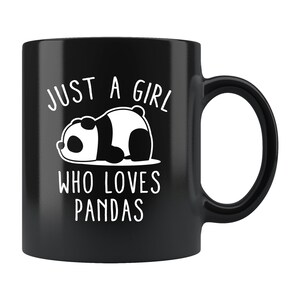 Könnte beinhalten: Schwarze Keramik-Tasse mit einer weißen Panda-Illustration und dem Text "JUST A GIRL WHO LOVES PANDAS". Der Panda liegt. Die Tasse hat einen gebogenen Henkel.