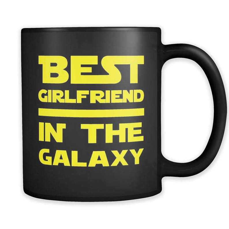 Pode incluir: Caneca de caf&eacute; preta com o texto "BEST GIRLFRIEND IN THE GALAXY" em amarelo.