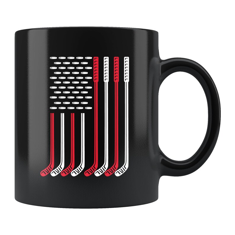 May include: Black coffee mug with a white and red hockey stick design that resembles the American flag.
