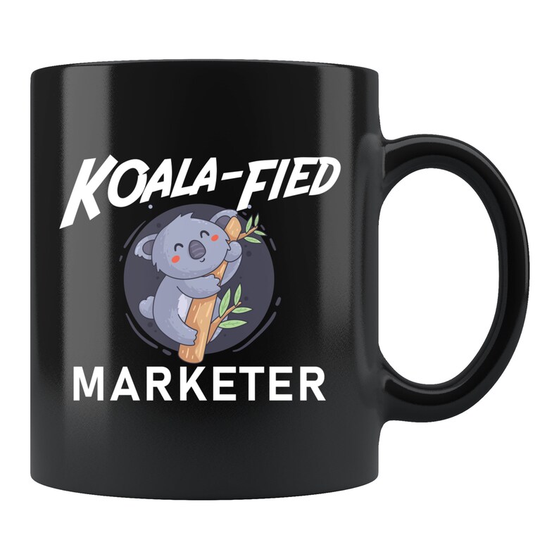 May include: Black coffee mug with a white graphic of a koala holding onto a tree branch. The text "KOALA-FIED MARKETER" is printed on the mug.