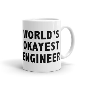May include: White ceramic mug with black text that reads "WORLD'S OKAYEST ENGINEER".