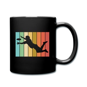 May include: Black coffee mug with a retro-style graphic of a person catching a frisbee. The graphic is set against a colorful striped background.