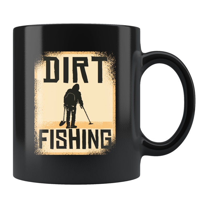 May include: Black ceramic mug with a white graphic of a person metal detecting with the text "DIRT FISHING" in a distressed font.