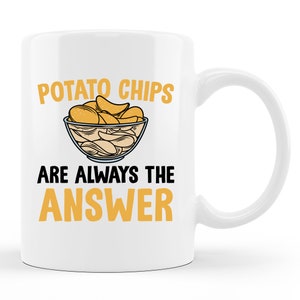 May include: White ceramic mug with a black and yellow design. The mug features a bowl of potato chips and the text "Potato Chips Are Always The Answer".