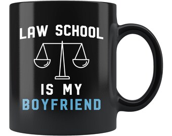 Può includere: Tazza da caffè nera con testo bianco che recita "Law School is my Boyfriend" e un grafico di bilancia bianco.
