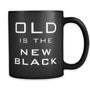 May include: Black coffee mug with white text that reads "OLD is the NEW BLACK".