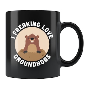May include: Black coffee mug with a white circle and the text "I Freaking Love Groundhogs" with a cartoon groundhog inside the circle.