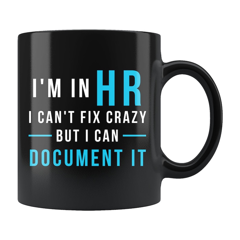 May include: Black coffee mug with white text that reads "I'm in HR I can't fix crazy but I can document it". The text "HR" is in blue.