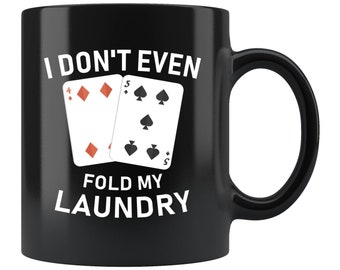 May include: Black coffee mug with white text that reads "I don't even fold my laundry" and a graphic of two playing cards, a four of diamonds and a five of spades.