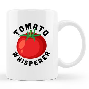 May include: White ceramic coffee mug with a black graphic of a tomato and the text "Tomato Whisperer".