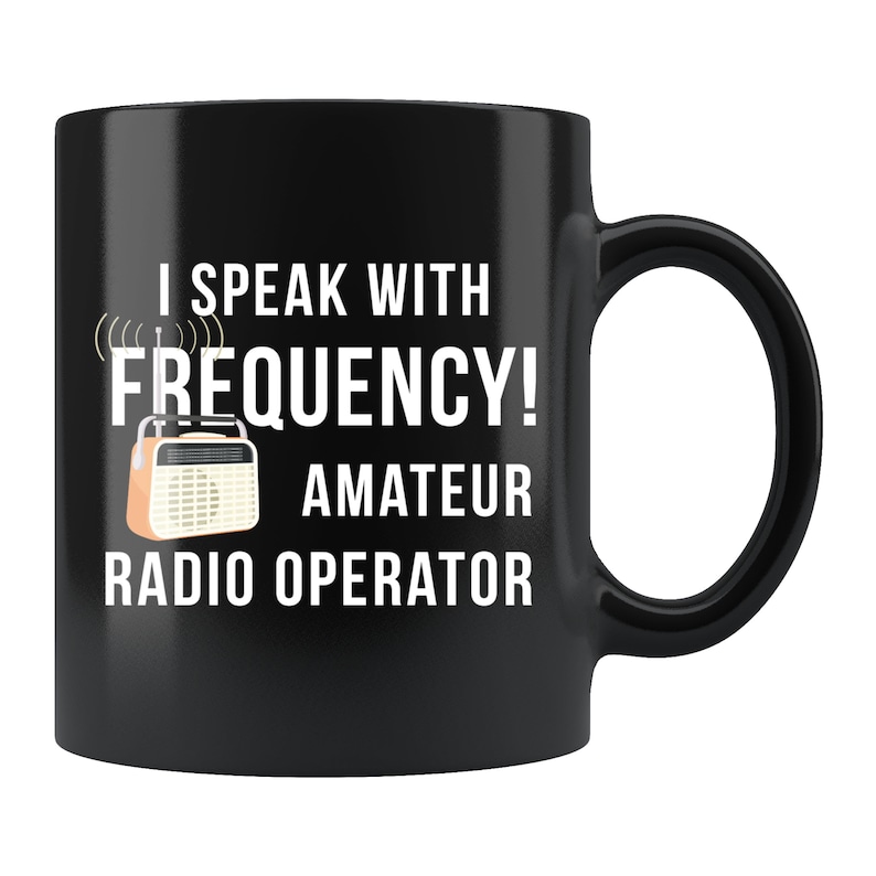 May include: Black coffee mug with white text that reads "I speak with frequency! Amateur Radio Operator". A vintage-style radio is pictured next to the text.