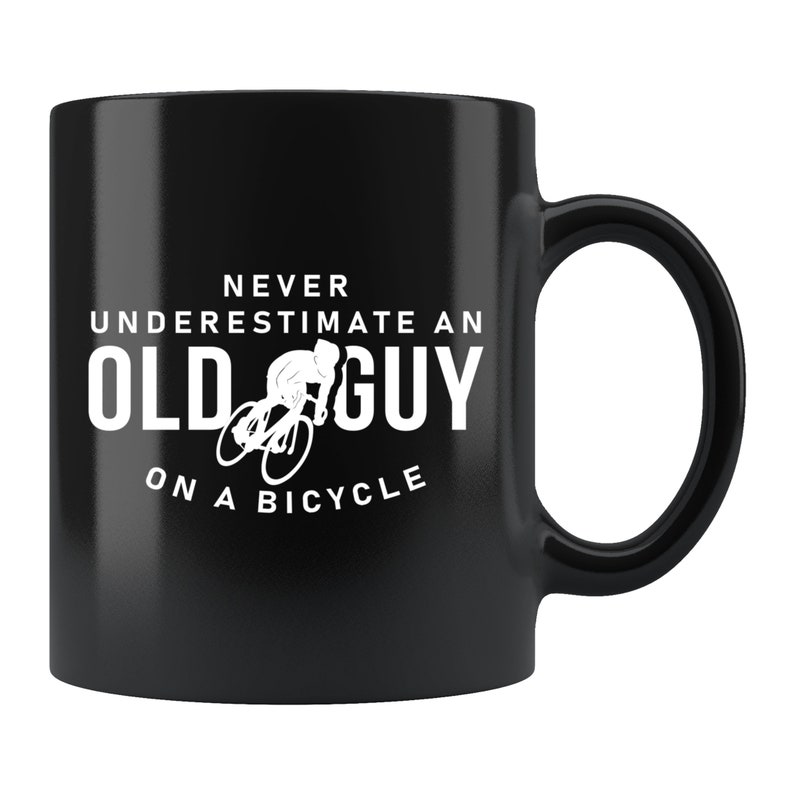May include: Black ceramic coffee mug with a white graphic that says "Never underestimate an old guy on a bicycle".