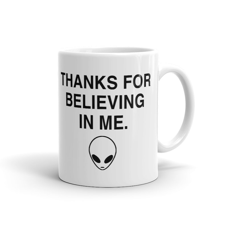 May include: White ceramic mug with black text that reads "Thanks for believing in me." and a black alien face graphic.