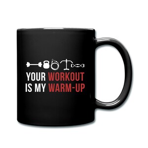 May include: Black coffee mug with white text that reads "Your workout is my warm-up". The text is accompanied by a row of white fitness icons including a dumbbell, kettlebell, jump rope, barbell, and a resistance band.
