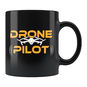 以下が含まれることがあります： オレンジ色の「DRONE PILOT」の文字と白いドローンが描かれた黒いセラミックマグカップ