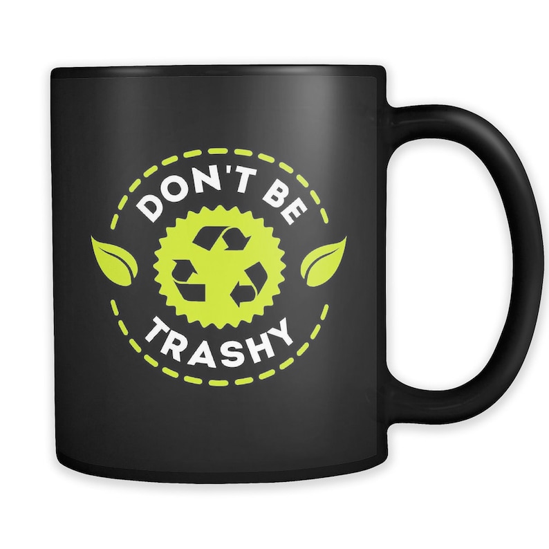 May include: Black ceramic coffee mug with a white design that says "Don't Be Trashy" with a green recycling symbol and leaves.