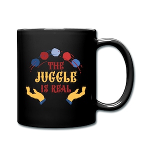 May include: Black coffee mug with a white design of juggling balls and the text "THE JUGGLE IS REAL".