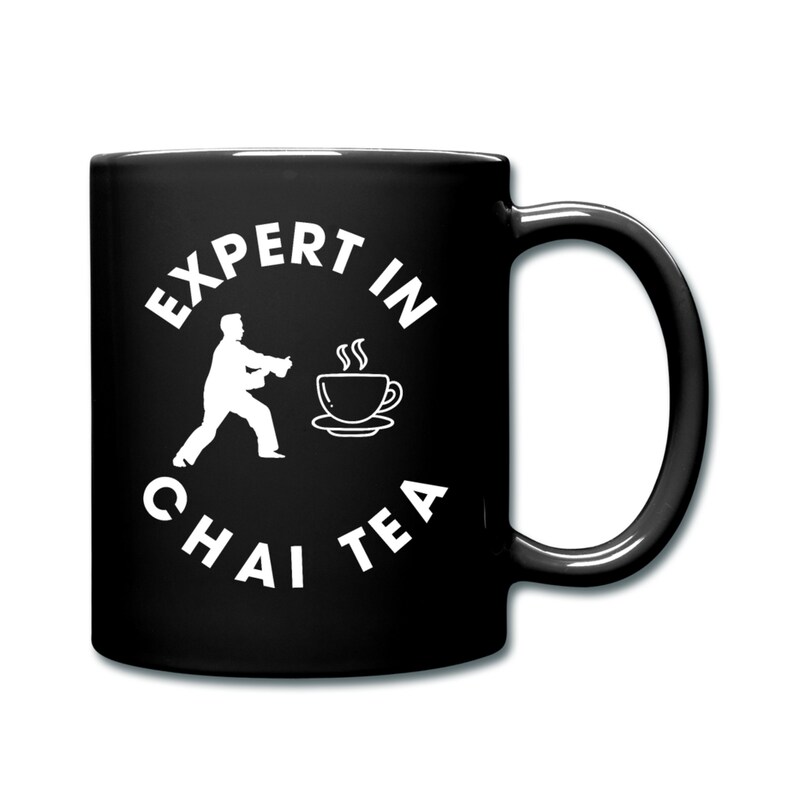 May include: Black ceramic mug with a white graphic of a person in a karate pose pouring tea into a cup. The text "Expert in Chai Tea" is written in a circle around the graphic.