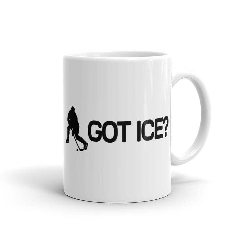 May include: White ceramic coffee mug with a black silhouette of a hockey player and the text "GOT ICE?" printed on it.