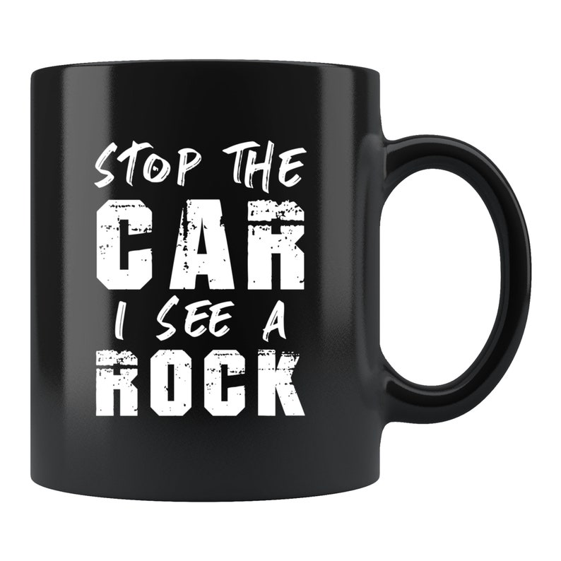 May include: Black ceramic coffee mug with white text that reads "Stop the car I see a rock".