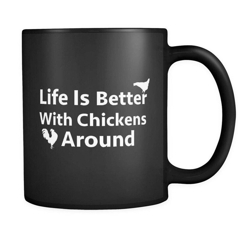 May include: Black ceramic coffee mug with white text that reads "Life Is Better With Chickens Around". The mug has a white silhouette of a chicken on the right side and a rooster on the left side.