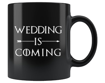 Może przedstawiać: Czarny ceramiczny kubek do kawy z białym tekstem "Wedding is Coming" ze strzałką skierowaną w prawo.