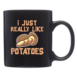 May include: Black ceramic coffee mug with a white graphic that says "I just really like potatoes" and a cartoon image of sliced potatoes.