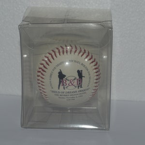Puede incluir: Una pelota de béisbol blanca con costuras rojas y una imagen en blanco y negro de dos figuras sosteniendo bates. La pelota de béisbol tiene el texto "Bolton Family Foundation for  Education" y "Michael Bolton Foundation for  Education" en la parte superior e inferior. El texto "B&B" está en el centro de la pelota. El texto "Field of Dreams Awards" está debajo del B&B. El texto "The Beverly Hilton Hotel" está debajo de los "Field of Dreams Awards". El texto "Sunday, November 6, 1994" está debajo del nombre del hotel.