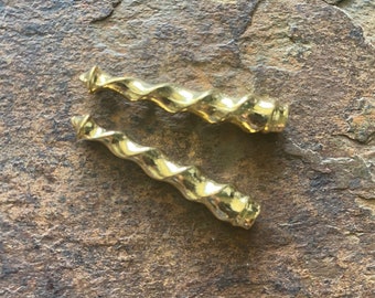 May include: Two gold-colored metal twisted decorative pieces. The pieces are about 2 inches long and have a spiral design.
