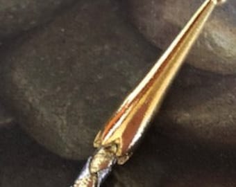 May include: A gold-toned metal stick with a braided design and a rounded tip. The stick is about 6 inches long.