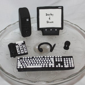 May include: Black and white computer themed cake decorations. The set includes a computer monitor with the text "Darby & Shane", a desktop computer, a keyboard, a phone, a headset, and a mouse.