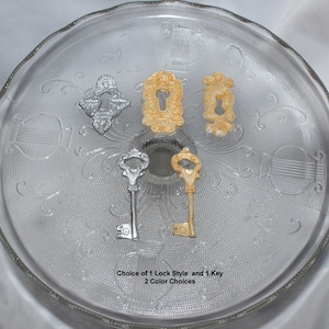 May include: Four decorative keyhole and key charms in gold and silver.  Choice of 1 Lock Style and 1 Key. 2 Color Choices.