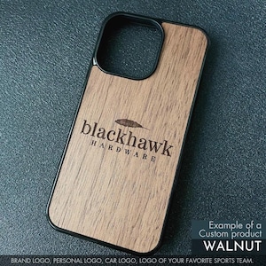 May include: A wooden phone case with a black border. The case features the engraved text "blackhawk HARDWARE" and a feather graphic. The case is made of walnut wood.