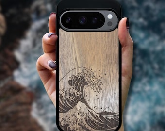 May include: A black smartphone case featuring a light brown wood grain back panel with a dark brown laser-engraved illustration of a large ocean wave and a small mountain peak in the background, with a black camera cutout at the top.