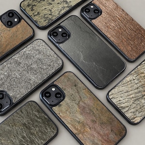 Puede incluir: Una colección de fundas para teléfonos inteligentes con varias texturas de piedra y vetas de madera. Las fundas tienen bordes negros y recortes para la cámara. Las texturas incluyen tonos de gris, marrón y verde, ofreciendo una estética natural.