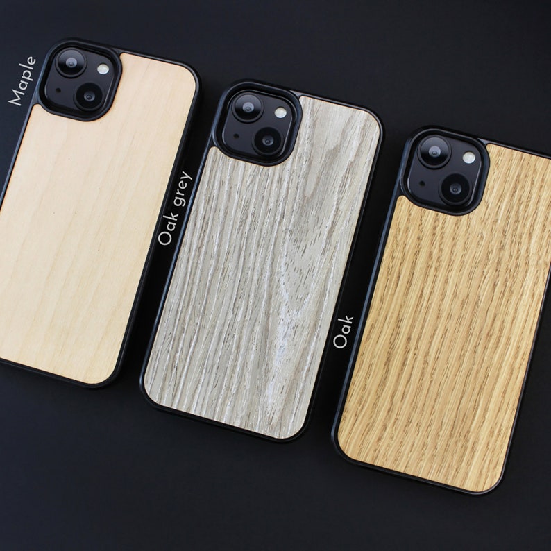 May include: Three phone cases with wooden textures. The case on the left is Maple, the middle case is Oak grey, and the case on the right is Oak. Each case has a black border.