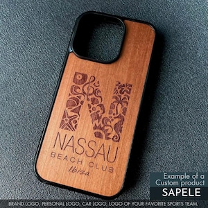 May include: Wooden phone case with a black border. The case features a large, engraved letter "N" filled with decorative elements. Below the letter, the text reads "NASSAU BEACH CLUB Ibiza". The case is made of Sapele wood.