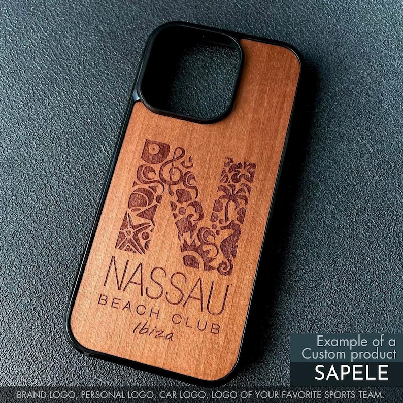 May include: Wooden phone case with a black border. The case features a large, engraved letter "N" filled with decorative elements. Below the letter, the text reads "NASSAU BEACH CLUB Ibiza". The case is made of Sapele wood.