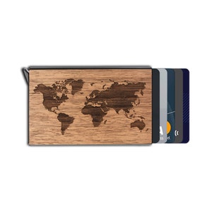 May include: A wooden card holder featuring a world map engraving. The holder is crafted from light brown wood and includes a metal clip. Several credit cards are partially visible, displaying a range of colours and designs.