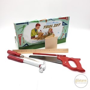 May include: A vintage "Future Builder Tool Set" box with illustrations of children building. The set includes a saw, hammer, screwdriver, ruler, and pencil. The tools have red handles and are arranged on a white surface.