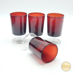 Peut inclure: Ensemble de quatre verres à vin en verre rouge avec des tiges transparentes. Les verres ont un effet de dégradé de couleur, passant d'un rouge plus foncé au bas à un rouge plus clair au sommet.