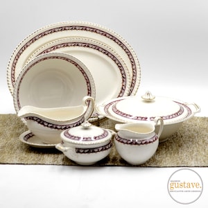 May include: A vintage set of white porcelain dinnerware with a burgundy and gold floral pattern. The set includes a large platter, a smaller plate, a bowl, a gravy boat, a sugar bowl, and a creamer.