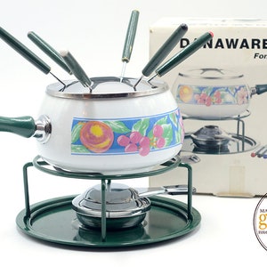 May include: White enamel fondue pot with a green handle and a floral design. The pot is on a green metal stand with a small burner. The set includes eight fondue forks with green handles.