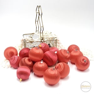 May include: A basket filled with red satin Christmas ornaments. The ornaments are arranged in a circular pattern and are all the same size. The basket is made of metal and has a gold finish.